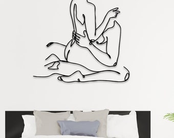May include: A black metal wall art sculpture depicting a couple in a romantic embrace. The sculpture is made of a single continuous line and has a minimalist design.