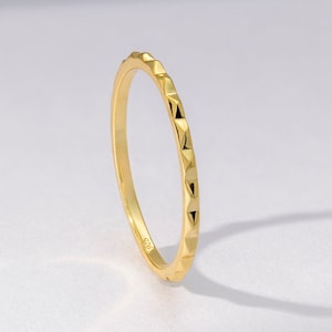 May include: A gold ring with a textured band of small triangles.