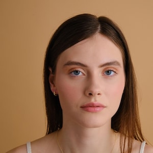 Puede incluir: Una mujer con el pelo largo y casta&ntilde;o que lleva un top blanco sin mangas y un collar de oro con un colgante de estrella de David.