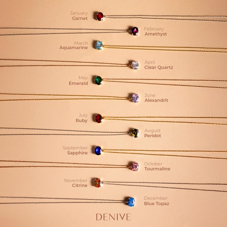 May include: A set of 12 necklaces with birthstone pendants. Each necklace features a different gemstone, representing the months of the year. The necklaces are arranged in a row, with the January pendant at the top and the December pendant at the bottom. The pendants are all small and round, and they are set in silver.