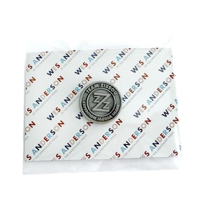 May include: A silver pin with the text "Team Zissou Expedition Jaguar Shark" and a stylized "ZZ" logo.