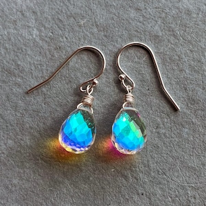 May include: A pair of silver teardrop earrings with iridescent blue and green crystal drops.