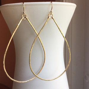 May include: A pair of gold teardrop-shaped earrings with a hammered finish.