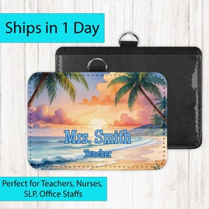 May include: A name badge holder with a tropical beach scene featuring palm trees, ocean waves, and a sunset. The name "Mrs. Smith" and the title "Teacher" are displayed in blue. A black holder with a metal ring is behind the badge.