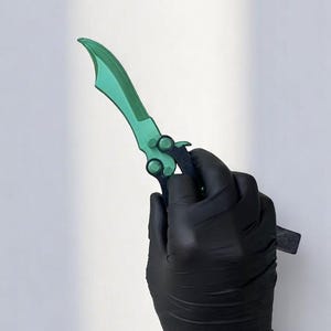 May include: A green and black butterfly knife with a curved blade. The blade is a vibrant green, and the handle is black. The knife is held by a gloved hand against a white background.