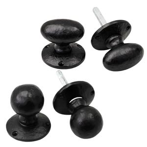 May include: A set of four black door knobs with a textured finish. Two knobs are oval-shaped and two are round-shaped. Each knob features a circular mounting plate with screw holes and a metal spindle extending from the back of the base.