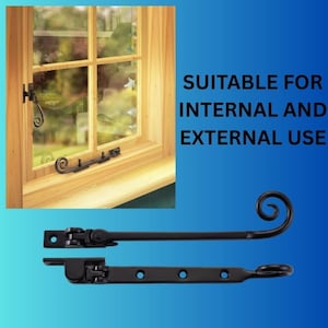 May include: Two black metal window stays featuring a scroll end design. One stay is shown installed on a wooden window frame, while two individual stays are displayed below with mounting holes and a hinged mechanism for securing windows.