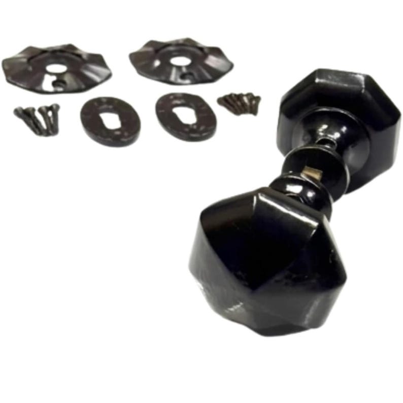 Puede incluir: Un pomo de puerta octogonal negro con acabado brillante, acompa&ntilde;ado de dos rosetas met&aacute;licas circulares, dos escudos ovalados para cerradura y una peque&ntilde;a colecci&oacute;n de tornillos de montaje negros a juego, formando un conjunto.