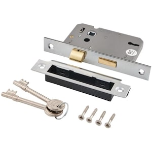 May include: A silver-toned metal mortise lock set featuring a rectangular lock body with brass-coloured latch and bolt, a matching strike plate with a black plastic insert, two silver keys on a ring, and four small silver-coloured mounting screws.