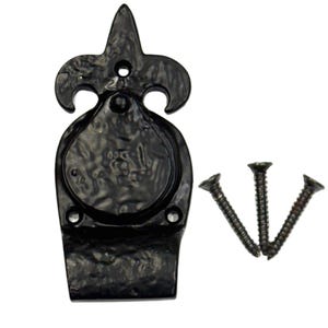 May include: A black metal door knocker featuring a fleur-de-lis top design with a circular centre and a rectangular base. The hardware includes three matching black screws positioned to the right of the door knocker for installation purposes.