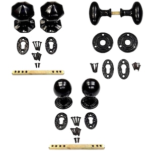 May include: A collection of black door hardware sets including three pairs of door knobs in octagonal, oval, and spherical shapes. Each set includes matching black escutcheon plates, circular rosettes, brass-colored spindles, and black mounting screws.