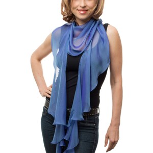 May include: A woman wearing a blue scarf with a ruffled edge, a black tank top, and blue jeans.