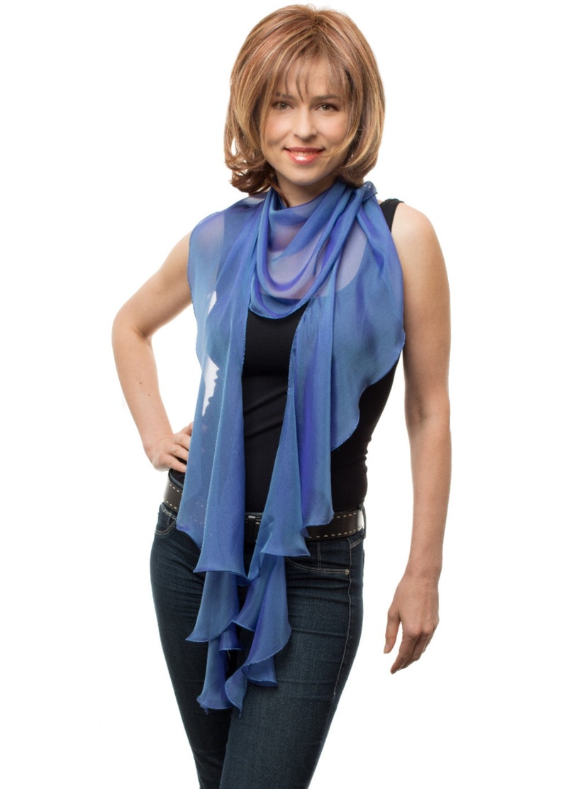 May include: A woman wearing a blue scarf with a ruffled edge, a black tank top, and blue jeans.