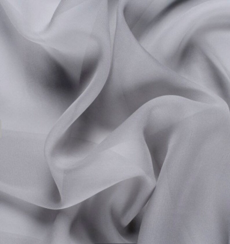 May include: A close-up of a light gray sheer fabric with soft folds and wrinkles.