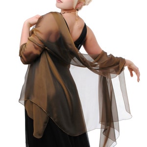 May include: A woman wearing a black dress with a brown sheer shawl draped over her shoulders. She is looking over her shoulder with a slight smile.