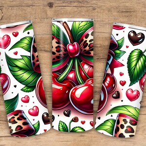 Puede incluir: Tres vasos aislados blancos con un tema de cerezas. Cada vaso presenta un dise&ntilde;o de cerezas, hojas verdes, corazones rojos y un lazo con estampado de leopardo. Los vasos est&aacute;n sobre un fondo de madera.