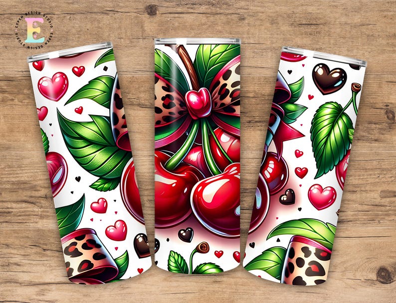 Puede incluir: Tres vasos aislados blancos con un tema de cerezas. Cada vaso presenta un dise&ntilde;o de cerezas, hojas verdes, corazones rojos y un lazo con estampado de leopardo. Los vasos est&aacute;n sobre un fondo de madera.