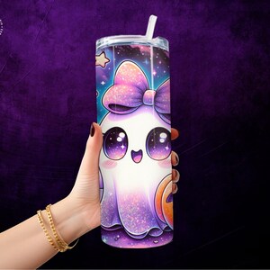 May include: A tall, cylindrical tumbler with a clear lid and straw. The tumbler features a cartoon ghost design with a large bow, starry background, and a jack-o'-lantern. The design is primarily purple, white, and orange.