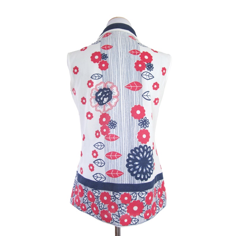 May include: White sleeveless top with a blue and pink floral print. The print features flowers, leaves, and stripes.