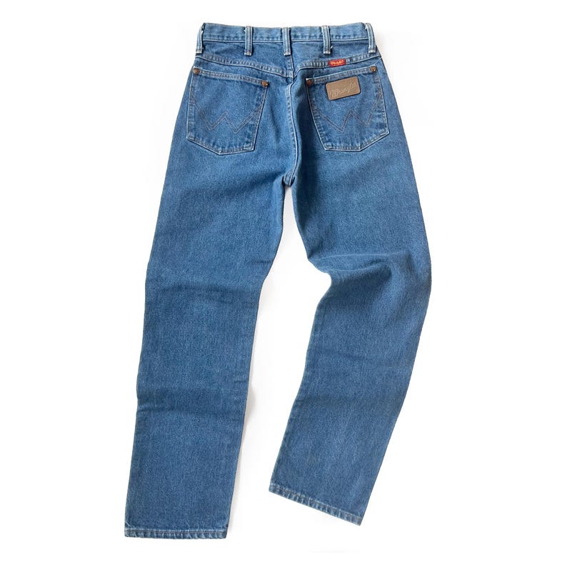 May include: Light blue denim jeans with a classic five-pocket design. The jeans feature a brown leather patch with the brand name on the back pocket. The jeans are made of durable denim material.