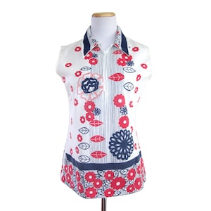 May include: A sleeveless white shirt with a blue and white striped collar and a zipper closure. The shirt has a red and blue floral pattern.