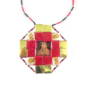 May include: A red and gold necklace with a square pendant featuring a religious image in the center. The pendant is made of small squares of red and gold paper.