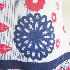 May include: White fabric with a blue and red floral pattern. The fabric features a large blue flower with white petals and a smaller red flower with a white center.