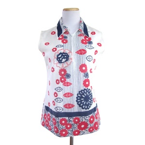 May include: A sleeveless white blouse with a blue collar and a zipper closure. The blouse features a red and blue floral print.