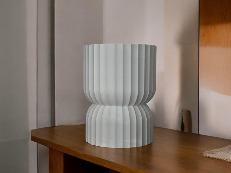 Modern table lamp, turned off, sitting on a wooden surface in a naturally sunlit room. Its minimalist design looks striking even when not illuminated, adding elegance and warmth to the inviting space.