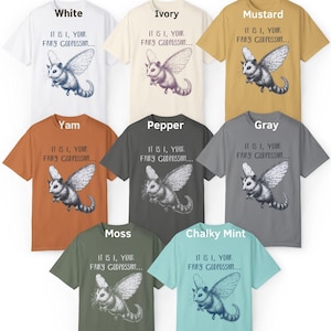 May include: A set of ten t-shirts featuring a flying opossum with the text "It is I, your fairy godpossum..." printed on the front. The shirts are available in a variety of colors, including white, ivory, mustard, yam, pepper, gray, moss, and chalky mint.