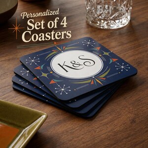 May include: A stack of four square coasters with a dark blue background, featuring a white circular center with the letters K&S in black. The design includes orange, teal, and olive green geometric starburst patterns and lines.