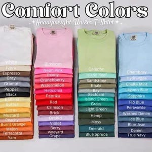 Op de afbeelding: Een kleurenkaart met 30 verschillende kleuren unisex T-shirts. De kleuren zijn gerangschikt in drie kolommen, waarbij elke kolom een ​​andere kleurtoon voorstelt. De kleuren omvatten wit, ivoor, espresso, grijs, graniet, peper, zwart, banaan, boter, citrus, mosterd, perzik, gebrande sinaasappel, meloen, terracotta, yam, bloesem, neonroze, pioenroos, kruisbes, watermeloen, heliconia, paprika, rood, karmijnrood, baksteen, orchidee, violet, bes, wijngaard, druif, celedon, eilandrif, zandsteen, kaki, baai, schuim, eilandgroen, gras, lichtgroen, hennep, mos, smaragd, blauwspar, chambray, hortensia, krijtwit, laguneblauw, saffier, floblauw, periwinkle, gewassen denim, ijsblauw, jeansblauw, denim, donkerblauw.