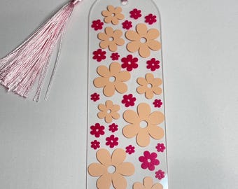 Peut inclure: Un marque-page en acrylique transparent avec un pompon rose. Le marque-page est décoré de fleurs pêche et rose.