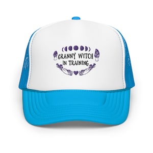 May include: A white and blue trucker hat with a purple embroidered design that says "Granny Witch in Training" with a moon and mushroom graphic.