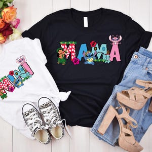 May include: Two t-shirts with a Stitch-themed design. The white shirt says "Mini" with Stitch characters and flowers. The black shirt says "Mama" with Stitch characters and flowers.