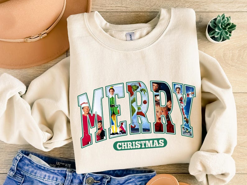 May include: A cream-colored sweatshirt with a green and white graphic print that says "MERRY CHRISTMAS" with images of characters from popular Christmas movies.