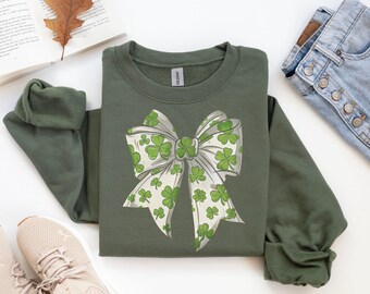 May include: A green sweatshirt with a white bow printed on the front. The bow is decorated with green shamrocks.