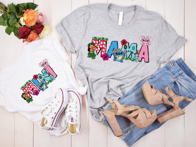 May include: Two white t-shirts with a colorful graphic print of the word "MAMA" and "MINI" with Stitch characters. The shirts are on a white wooden surface with a bouquet of red roses and a pair of white sneakers.