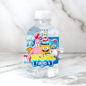 May include: A clear plastic water bottle with a white cap. The bottle is decorated with a colourful sticker featuring cartoon characters from the SpongeBob SquarePants series. The sticker reads "MICHAEL TURNS 4".