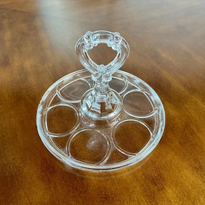 May include: A clear glass serving tray with a handle. The tray has six individual compartments for holding small items.