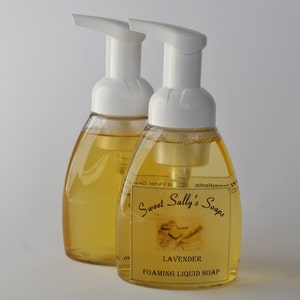 May include: Two amber glass bottles of foaming liquid soap with white pumps. The bottles have labels that say "Sweet Sally's Soaps" and "Lavender Foaming Liquid Soap".