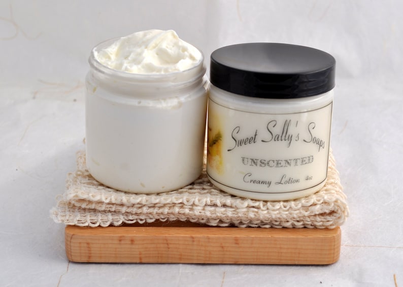 May include: Two jars of unscented creamy lotion. The jar on the left is full of white lotion. The jar on the right is labeled "Sweet Sally's Soaps Unscented Creamy Lotion".