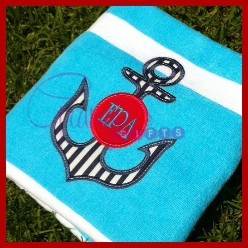 Op de afbeelding: Een blauw-wit gestreepte anker met een rode cirkel met het monogram "EPA" op een turquoise en wit gestreepte strandhanddoek.