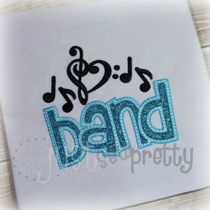 May include: Blue and white glitter embroidered design of the word "band" with musical notes and a treble clef.