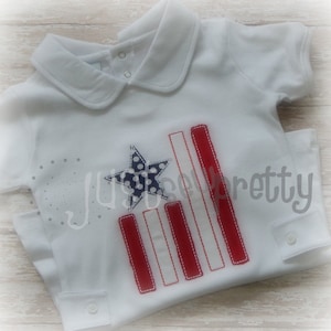 May include: White baby onesie with a red, white, and blue embroidered American flag design. The flag has a blue star with white polka dots in the top left corner and red and white stripes.