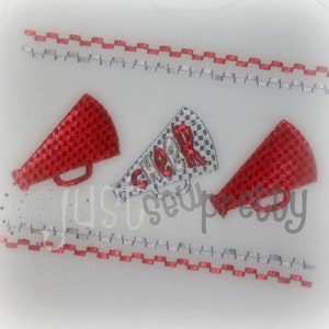 May include: Three red and white megaphones with the word "CHEER" embroidered on one of them. The megaphones are on a white background with a red and white stitched border.