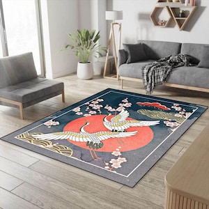 May include: A blue and gray area rug with a red and white sun and two white cranes with black accents. The rug has a border of white and gray.