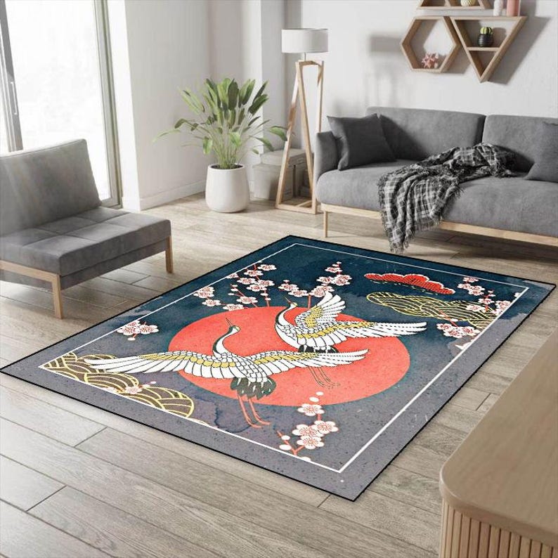 May include: A blue and gray area rug with a red and white sun and two white cranes with black accents. The rug has a border of white and gray.
