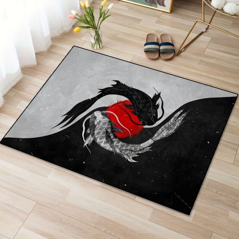 May include: Black and white rug with a yin yang design featuring two fish swimming around a red circle. The rug has a gray background.