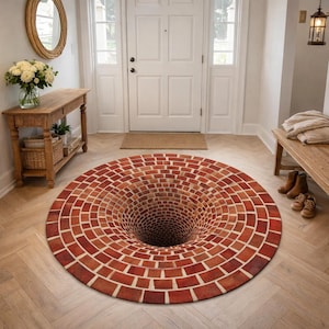 Puede incluir: Una alfombra redonda con un diseño de ilusión óptica en 3D. La alfombra presenta un patrón de ladrillos en tonos rojos y marrones, creando la apariencia de un agujero profundo o vórtice en el centro. La alfombra está colocada sobre un suelo de madera clara.